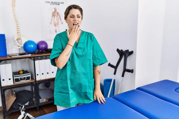 Young Hispanic Woman Wearing Physiotherapist Uniform Standing Clinic Bored Yawning — Photo