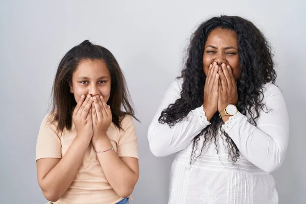 stock image Mother and young daughter standing over white background laughing and embarrassed giggle covering mouth with hands, gossip and scandal concept 