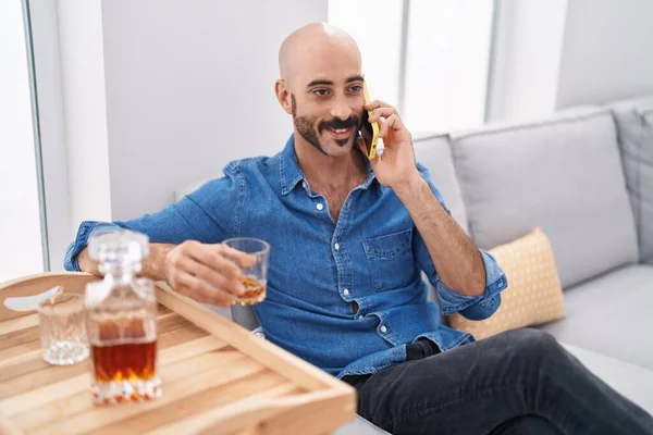 Young Hispanic Man Talking Smartphone Drinking Whisky Home —  Fotos de Stock