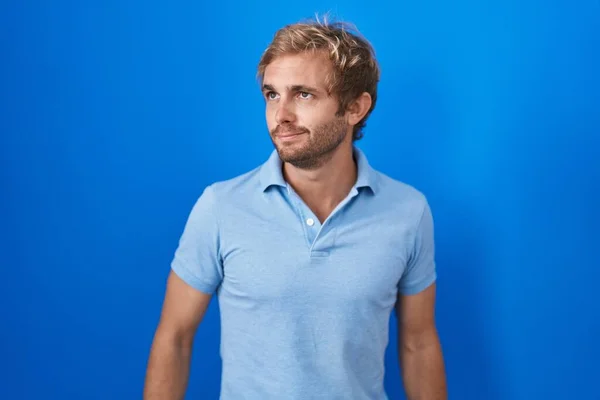 Homme Caucasien Debout Sur Fond Bleu Souriant Regardant Vers Côté — Photo