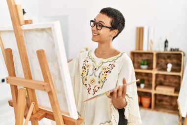 Genç İspanyol kadın resim stüdyosunda kendine güvenen gülümsüyor.