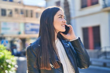 Parktaki akıllı telefondan konuşan, kendine güvenen genç bir kadın.