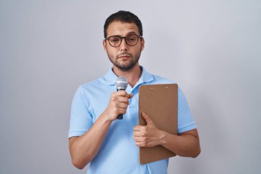 Gazeteci mikrofon tutan İspanyol bir adam şüpheci ve gergin bir pano, sorun yüzünden surat asıyor. negatif kişi. 