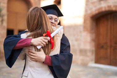 Man and woman mother and son hugging each other celebrating graduation at university clipart