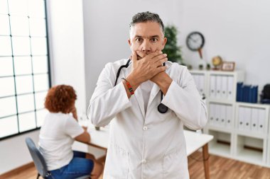 Hastanedeki orta yaşlı bir doktor ve bir hasta yanlışlıkla elleriyle ağzını kapatmış. gizli kavram. 