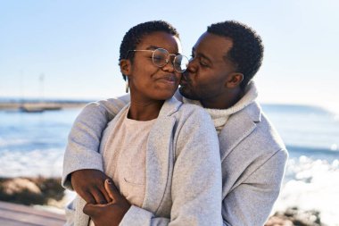 Erkek ve kadın çift sahilde birbirlerine sarılıyorlar.