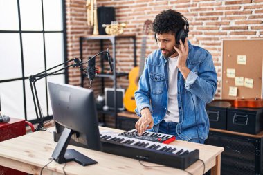 Genç Arap müzisyen müzik stüdyosunda piyano klavyesi çalıyor.