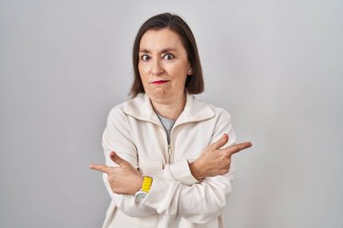 Soyutlanmış arka planda duran orta yaşlı İspanyol kadın her iki tarafı da parmaklarıyla işaret ediyor, farklı yönler farklı. 