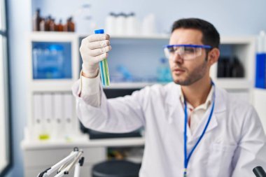 Laboratuvarda test tüpleri tutan genç İspanyol bilim adamı.