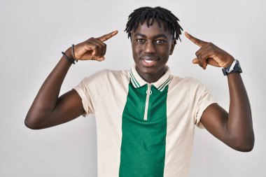 Münzevi arka planda duran Afrikalı adam iki eliyle başını gösteren gülümseme, harika bir fikir ya da düşünce, iyi bir hafıza 