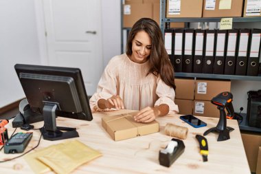 Young hispanic woman smiling confident packing order at storehouse