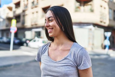 Young beautiful hispanic woman smiling confident looking to the side at street