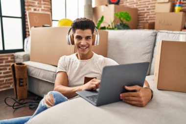 Genç İspanyol adam yeni evinde müzik dinlerken kendinden emin gülümsüyor.