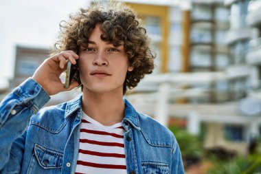 Genç İspanyol adam şehirde telefonla konuşuyor.