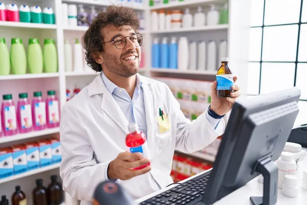Fiatal Spanyol Férfi Gyógyszerész Mosolyog Magabiztos Gazdaság Gyógyszeres Üvegek Gyógyszertárban — Stock Fotó