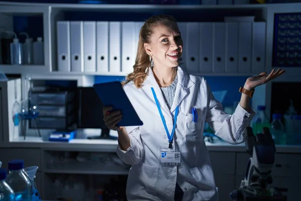 夜遅くに科学研究所で働いている美しいブロンドの女性は脇に手を指していますオープン手のひらショーコピースペース 提示広告笑顔興奮幸せ — ストック写真