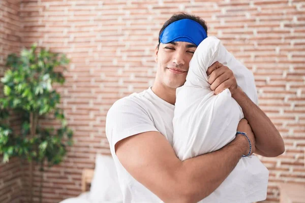 Young Hispanic Man Wearing Sleep Mask Hugging Pillow Bedroom — Stockfoto