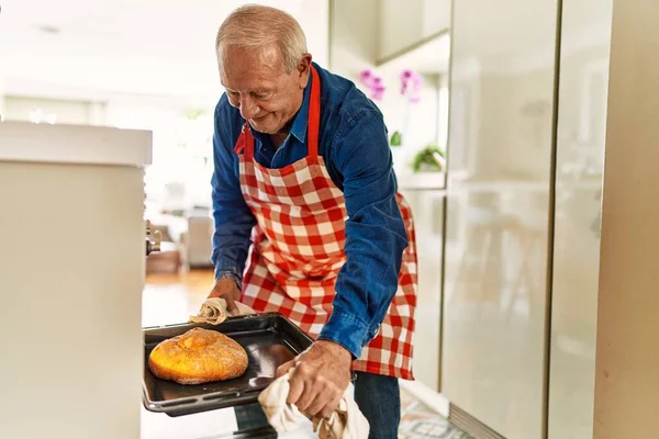 Senior Man Putting Bread Oven Kitchen — Stock fotografie