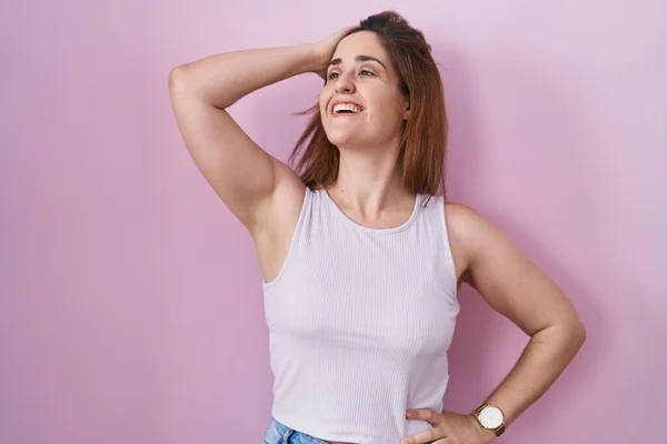 Brunette Woman Standing Pink Background Smiling Confident Touching Hair Hand — Stockfoto