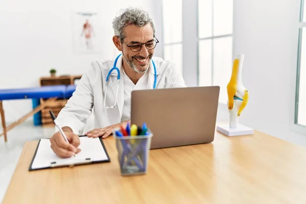 Średni Wiek Siwy Mężczyzna Lekarz Pomocą Laptopa Pisania Dokumencie Klinice — Zdjęcie stockowe