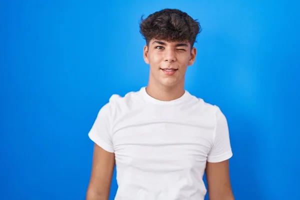 Hispanischer Teenager Der Vor Blauem Hintergrund Steht Und Augenzwinkernd Die — Stockfoto