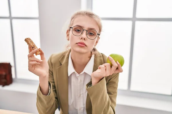 Young Caucasian Woman Working Office Eating Snack Relaxed Serious Expression — Stockfoto