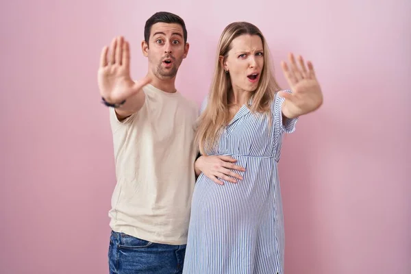 Young Couple Expecting Baby Standing Pink Background Doing Stop Gesture — Stock Photo, Image