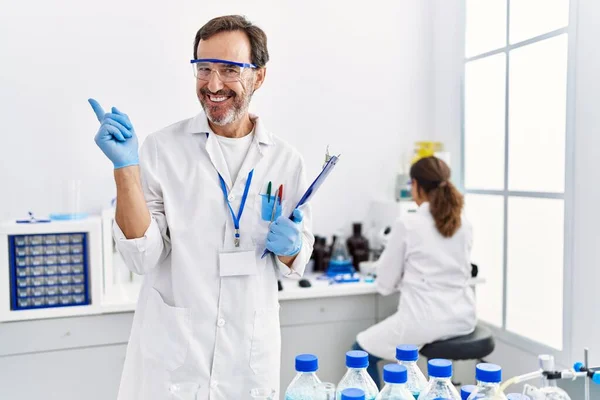 Мужчина Средних Лет Работающий Научной Лаборатории Улыбается Счастливо Указывая Рукой — стоковое фото