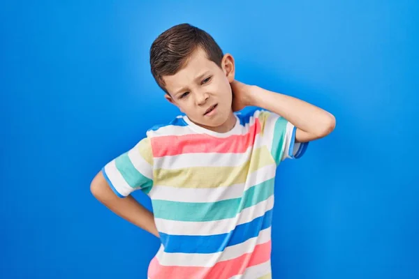 年轻的高加索小孩站在蓝色的背景上 颈部疼痛 手摸脖子 肌肉疼痛 — 图库照片