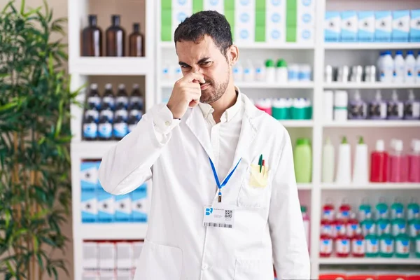 Handsome Hispanic Man Working Pharmacy Drugstore Smelling Something Stinky Disgusting — Zdjęcie stockowe