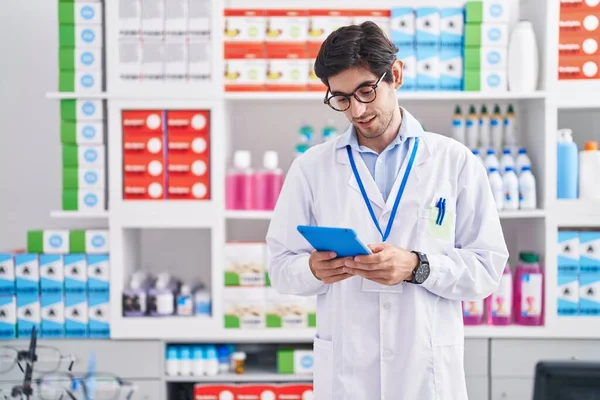 Young Hispanic Man Pharmacist Using Touchpad Relaxed Expression Pharmacy — Foto de Stock