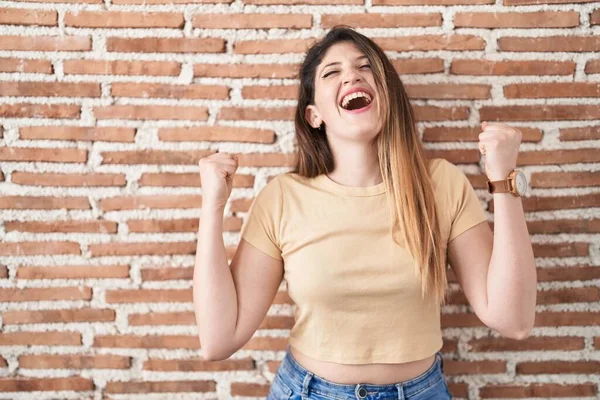 Jonge Brunette Vrouw Staat Bakstenen Muur Vieren Verrast Verbaasd Voor — Stockfoto