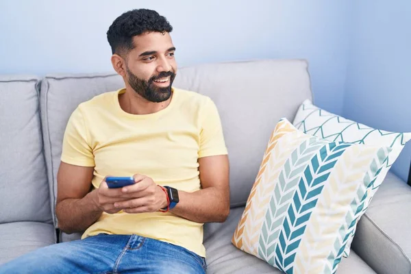 Young Arab Man Using Smartphone Sitting Sofa Home — ストック写真