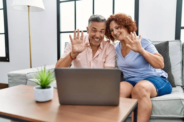 Middle age man and woman couple using laptop having video call sitting on sofa at home