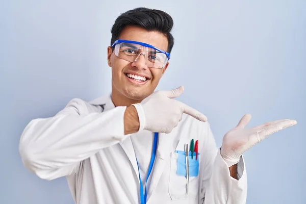 Latynos Pracujący Jako Naukowiec Zdumiony Uśmiechnięty Kamery Prezentując Się Ręką — Zdjęcie stockowe