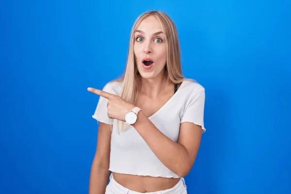 Young Caucasian Woman Standing Blue Background Surprised Pointing Finger Side — Stock Photo, Image