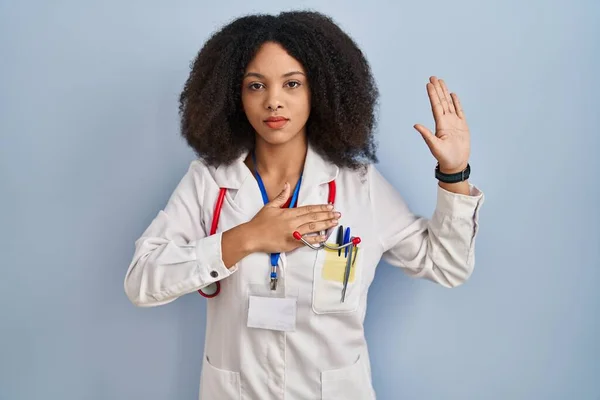 医師の制服を着た若いアフリカ系アメリカ人女性胸と開いた手のひらに手で身に着けている聴診器 忠誠の誓いを作る — ストック写真