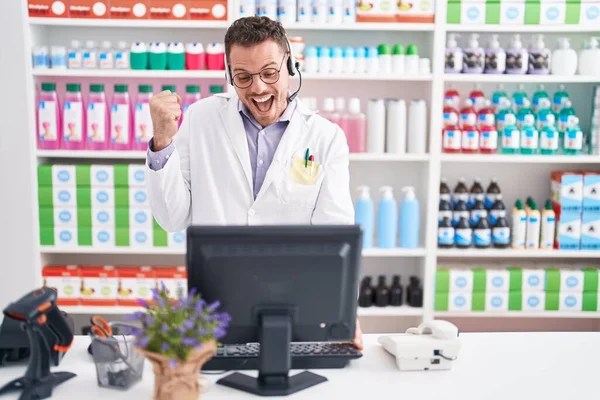 Jovem Hispânico Trabalhando Farmácia Farmácia Usando Fone Ouvido Gritando Orgulhoso — Fotografia de Stock