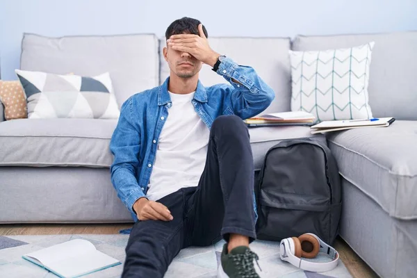 Young Hispanic Man Sitting Floor Studying University Covering Eyes Hand — Zdjęcie stockowe