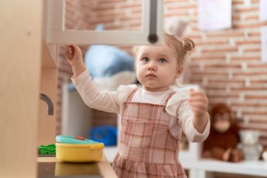 Sevimli beyaz kız kreşte oyun mutfağıyla oynuyor.