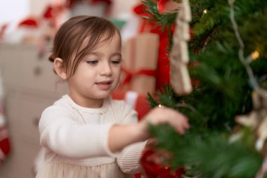 Noel ağacını süsleyen sevimli kız evde duruyor.