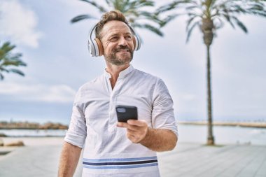 Deniz kenarında akıllı telefon kullanan orta yaşlı bir adam.