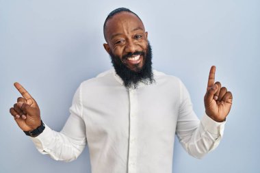 African american man standing over blue background smiling confident pointing with fingers to different directions. copy space for advertisement 