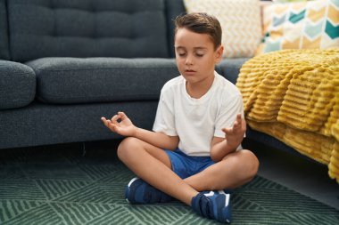 Sevimli İspanyol bebek yoga yapıyor. Evde yerde oturuyor.