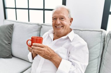 Son sınıf öğrencisi evdeki kanepede oturup kahve içiyor.