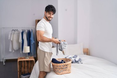 Genç İspanyol adam gülümsüyor. Yatak odasında ev işi yaptığından emin.