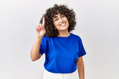 Young middle eastern woman standing over isolated background pointing finger up with successful idea. exited and happy. number one. 