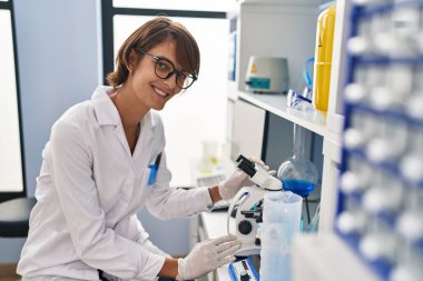 Laboratuvarda mikroskop kullanan genç ve güzel İspanyol bilim kadını.