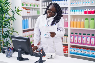 Eczanede telefon okuyarak konuşan Afrikalı Amerikalı kadın eczacı.