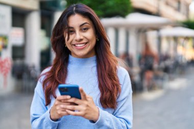 Sokakta akıllı telefon kullanan, kendine güvenen genç İspanyol kadın.